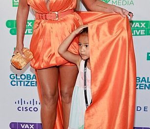 Chrissy Teigen wows in busty orange mini dress as she arrives with daughter Luna to Global Citizen Vax Live concert in LA